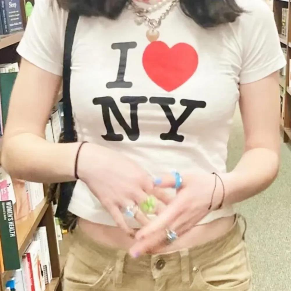 A person wearing a white crop top with the text 'I ❤️ NY' printed on the front.