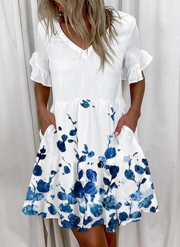 A woman wearing a white knee-length dress with blue floral print, V-neckline, and lotus leaf short sleeves.