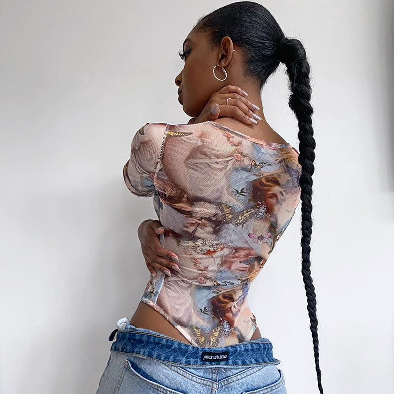 A woman modeling a long sleeve bodysuit with a printed design, wearing denim pants and accessorized with a watch and earrings.