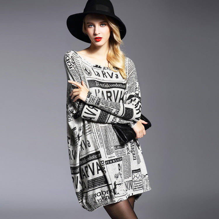 A woman wearing a long-sleeved pullover with a newspaper-inspired print design. The pullover is predominantly in beige and light gray tones.