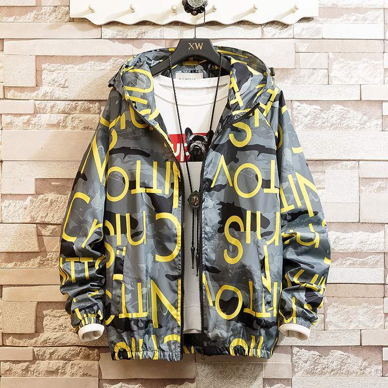 Hoodie coat with a graphic print design in black, white, and yellow colors, displayed on a mannequin against a brick wall background.