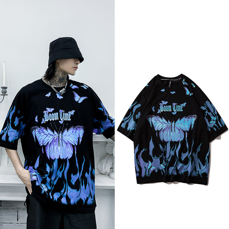 A person wearing a black round neck t-shirt with a graphic print of blue and purple butterflies.