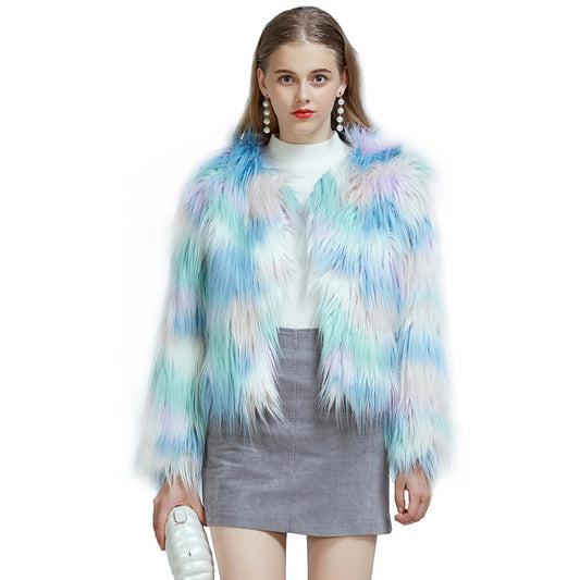 A woman wearing a multicolored gradient faux fur jacket with long sleeves, paired with a white top and a gray skirt.