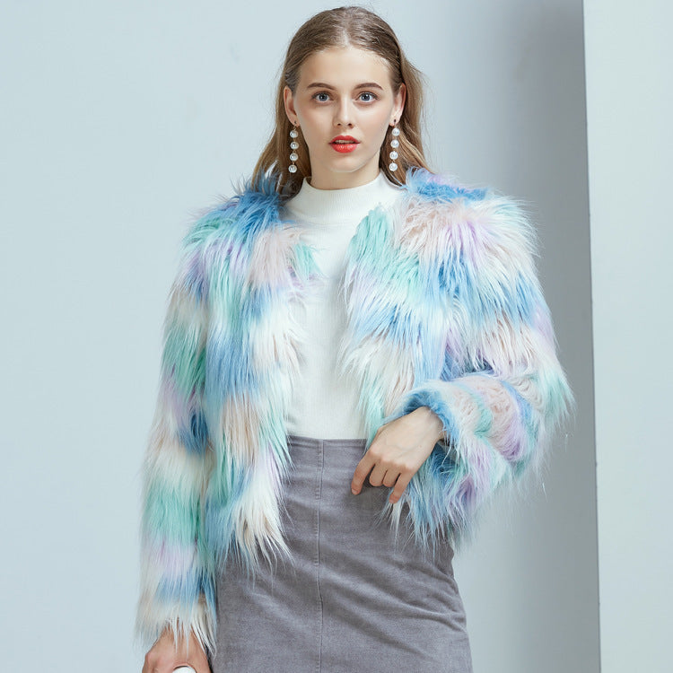 A woman wearing a multicolored gradient faux fur jacket with long sleeves, paired with a white top and a gray skirt.