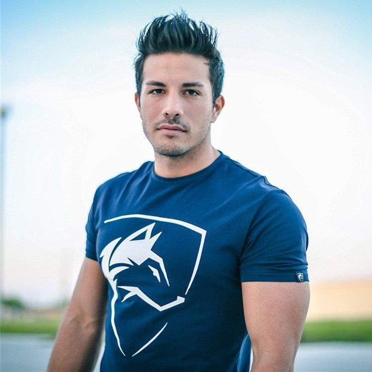 A man standing outdoors wearing a black Iron Raven Gymwear t-shirt with a logo on the front.