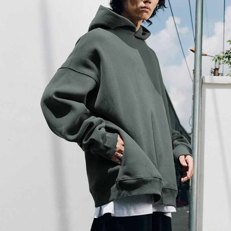 A person wearing a dark grey Urban Fade Washed Pullover Hoodie with a high hood and oversized fit, paired with black pants. The hoodie has a washed character print on the front.