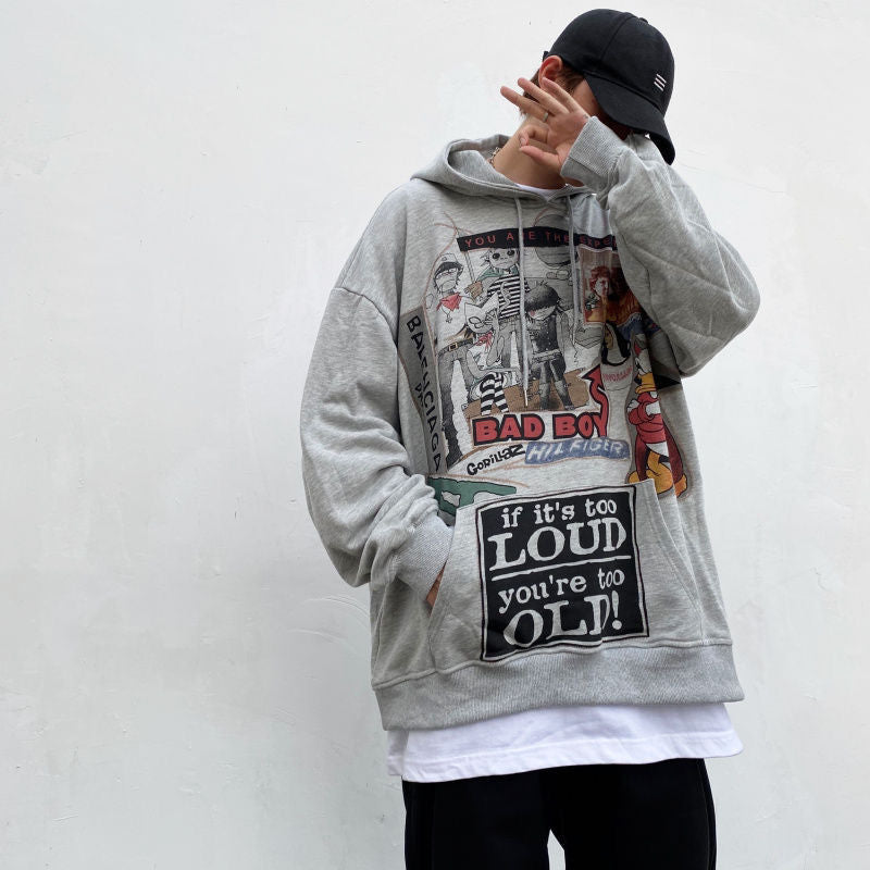 A person wearing a gray Urban Rebel graphic sweatshirt with a hood, featuring a bold, cartoon-inspired design.