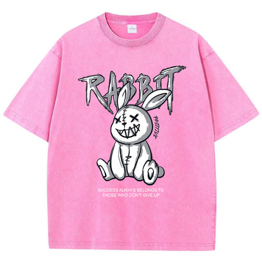 A pink T-shirt featuring a graphic print of a stylized rabbit with the text 'RABBIT' above it. The graphic has a black and white color scheme.