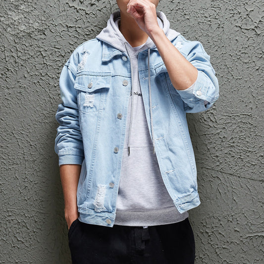 A person wearing a light blue denim jacket with a hood, over a white t-shirt, paired with black pants.