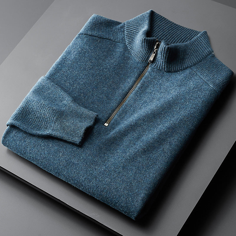 A blue oversized cardigan with a zipper at the neck, laid flat on a grey surface.