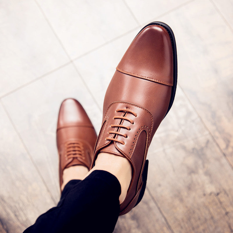 A pair of black, lace-up, professional dress shoes viewed from above, with the wearer's lower legs visible.