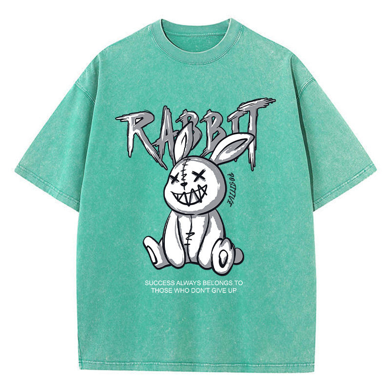 A green T-shirt featuring a graphic print of a stylized rabbit with the text 'RABBIT' above it. The graphic has a black and white color scheme.