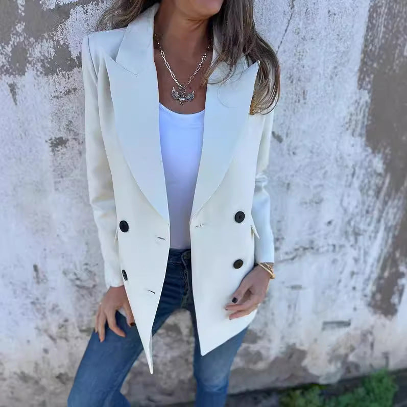 A woman wearing a white Urban Grace Lapel Jacket with a white top and blue jeans. She has accessorized with a necklace and has convenient pockets on the jacket.