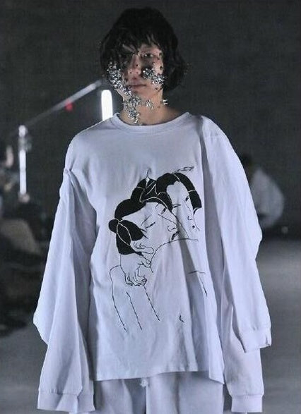 A person wearing a black long sleeve sweater with a graphic design in white.