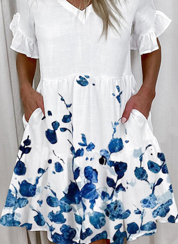 A woman wearing a white knee-length dress with blue floral print, V-neckline, and lotus leaf short sleeves.