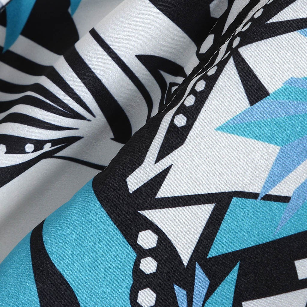 A short-sleeved Urban Luau shirt with a geometric pattern featuring black, white, yellow, and blue colors, displayed on a wooden hanger.