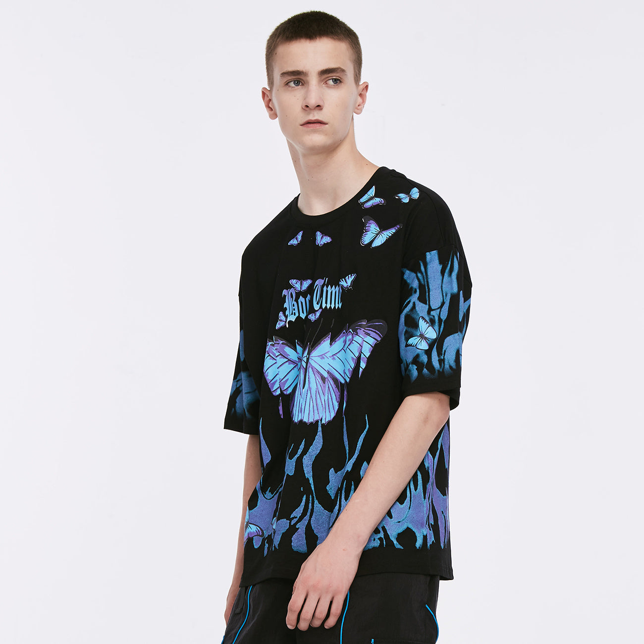 A person wearing a black round neck t-shirt with a graphic print of blue and purple butterflies.