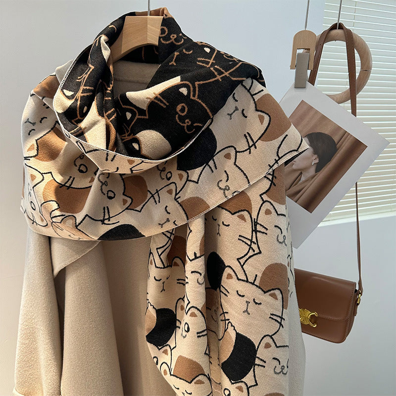 A beige and brown artificial cashmere scarf with a cat pattern, displayed on a mannequin alongside other winter clothing items.