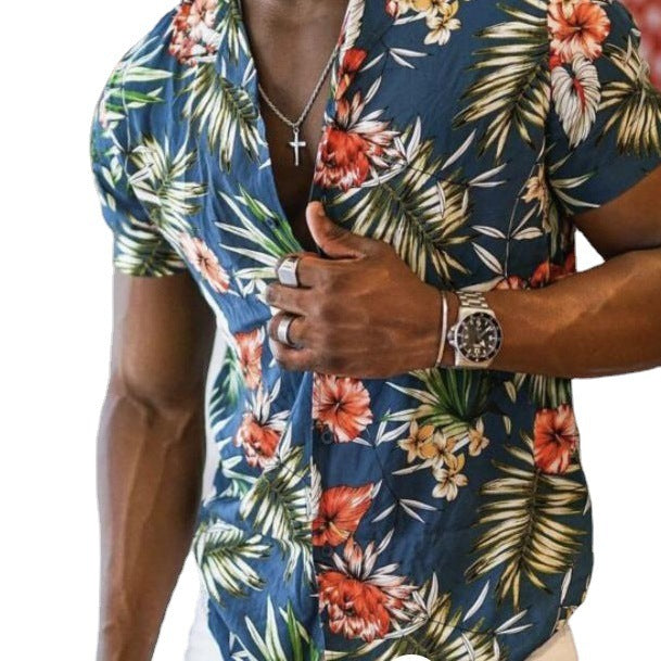 A man wearing a green Urban Crest button-up shirt with a floral pattern consisting of leaves and flowers, in a room with a red and white patterned wall.