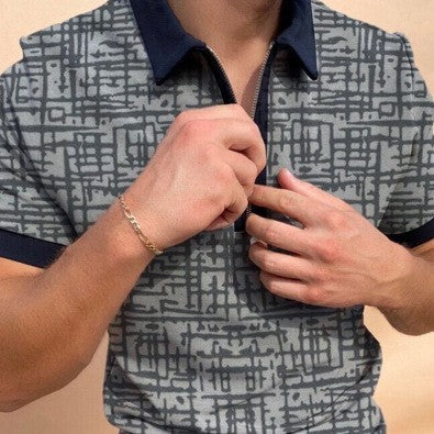 A person wearing a short-sleeved button-up shirt with a geometric pattern, in the process of buttoning the shirt.