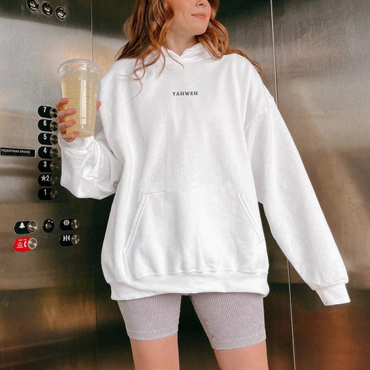 A woman wearing a white hoodie with a bold black 3D letter print, paired with gray bicycle shorts, standing inside an elevator.