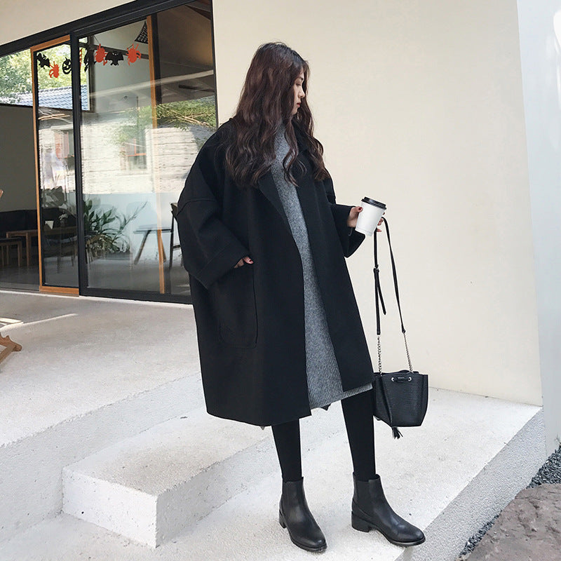 A person wearing a black Urban Ember Wool Wrap coat with a turtleneck sweater underneath, standing indoors.