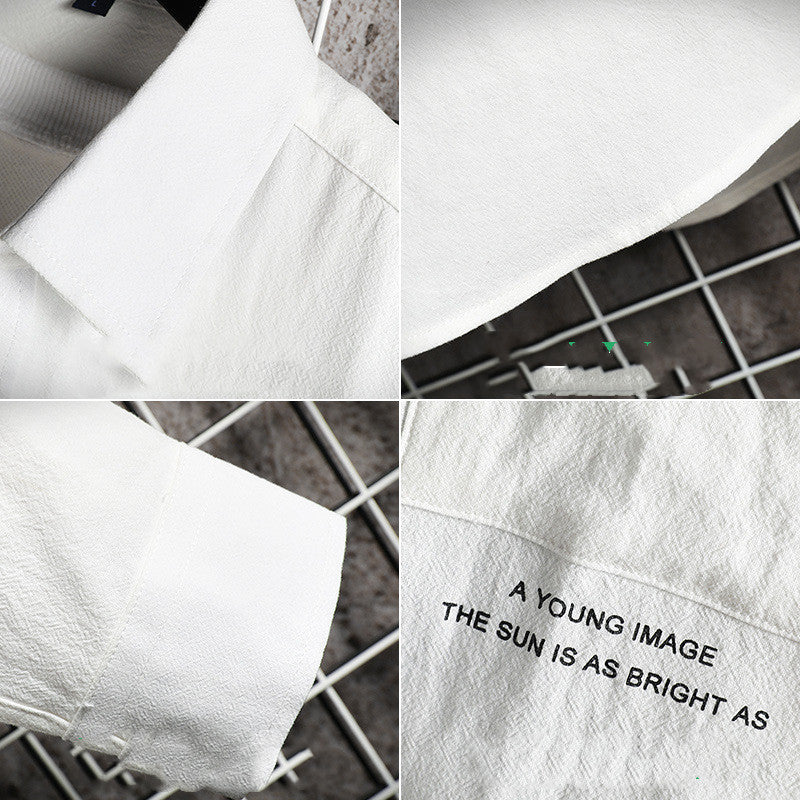 A male fashion model wearing a white Urban Wave men's fashion top with a lapel collar, long sleeves, and a slim fit. The top is displayed in an urban setting with a tiled wall in the background.