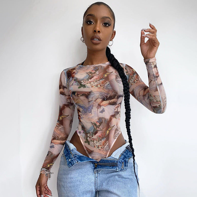 A woman modeling a long sleeve bodysuit with a printed design, wearing denim pants and accessorized with a watch and earrings.