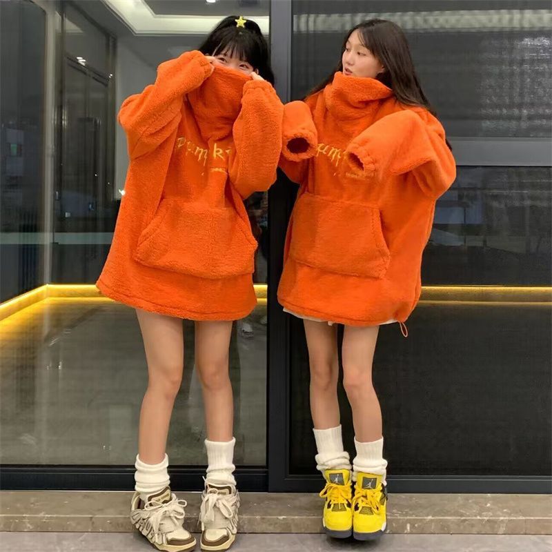 Person wearing an orange hoodie with a reflective surface, standing in front of a mirror.