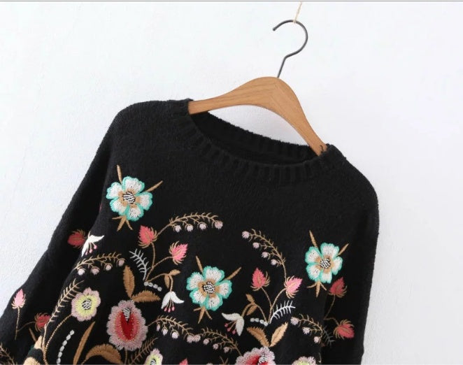 A black pullover with colorful floral embroidery displayed on a mannequin.