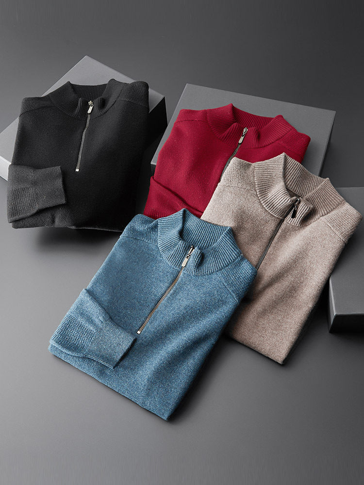 A black, red, blue, and brown oversized cardigan with a zipper at the neck, laid flat on a grey surface.