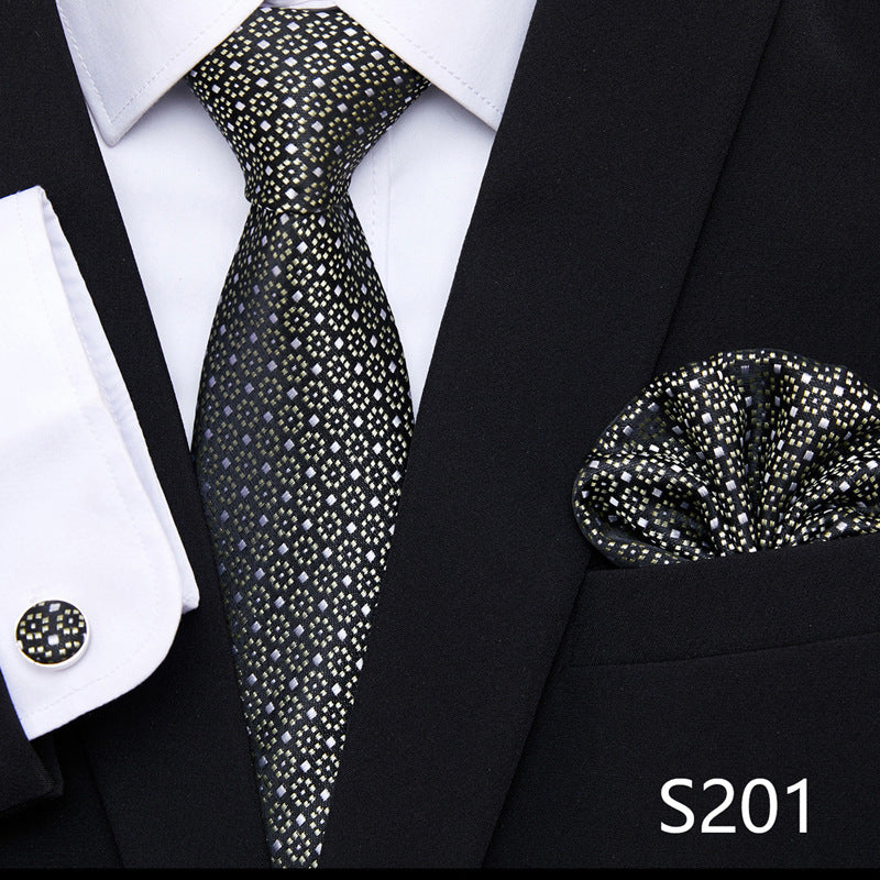 A set of men's formal wear accessories including a tie, pocket square, and cufflinks. The tie features a dotted pattern, the pocket square is folded, and the cufflinks are round.