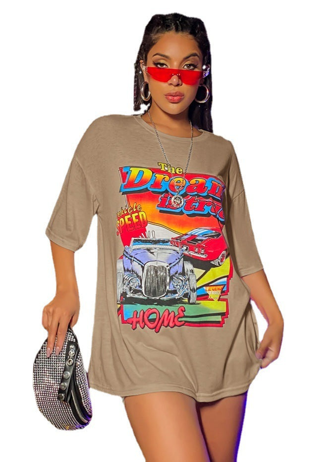 A woman wearing an oversized top with a graphic print, paired with shorts and red sunglasses.