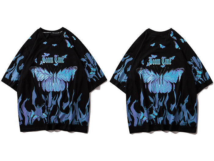 A person wearing a black round neck t-shirt with a graphic print of blue and purple butterflies.
