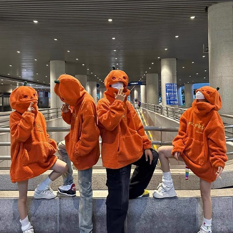 Five people wearing orange hoodies with animal face designs in a public area.