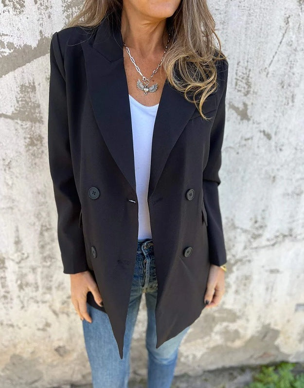 A woman wearing a black Urban Grace Lapel Jacket with a white top and blue jeans. She has accessorized with a necklace and has convenient pockets on the jacket.