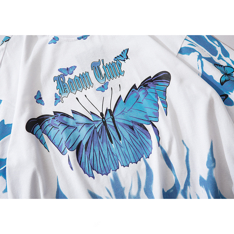 A person wearing a black round neck t-shirt with a graphic print of blue and purple butterflies.