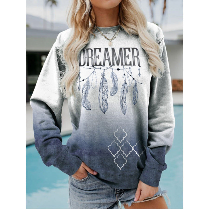 Person wearing a sweatshirt with 'DREAMER' and feather design, standing by a pool.