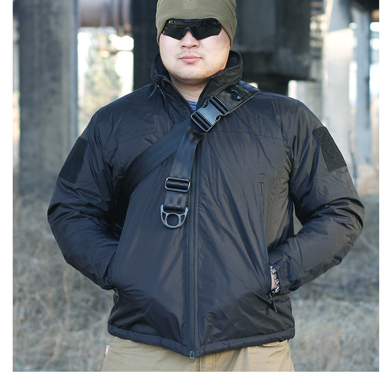 A person wearing a camouflage waterproof coat with a hood, sunglasses, and a beanie. They are standing in a dilapidated building setting.