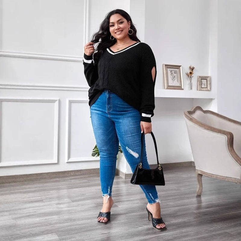 A woman wearing a black plus-sized cozy knit sweater with color-blocking design, featuring a V-neck and long sleeves.