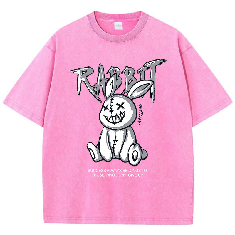 A pink T-shirt featuring a graphic print of a stylized rabbit with the text 'RABBIT' above it. The graphic has a black and white color scheme.