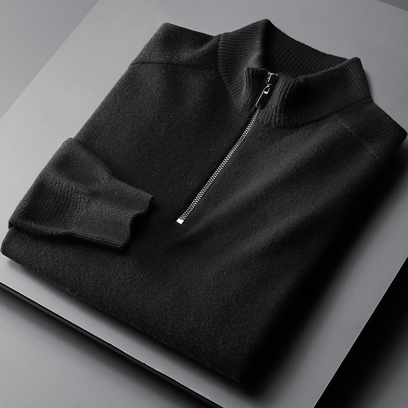A black oversized cardigan with a zipper at the neck, laid flat on a grey surface.