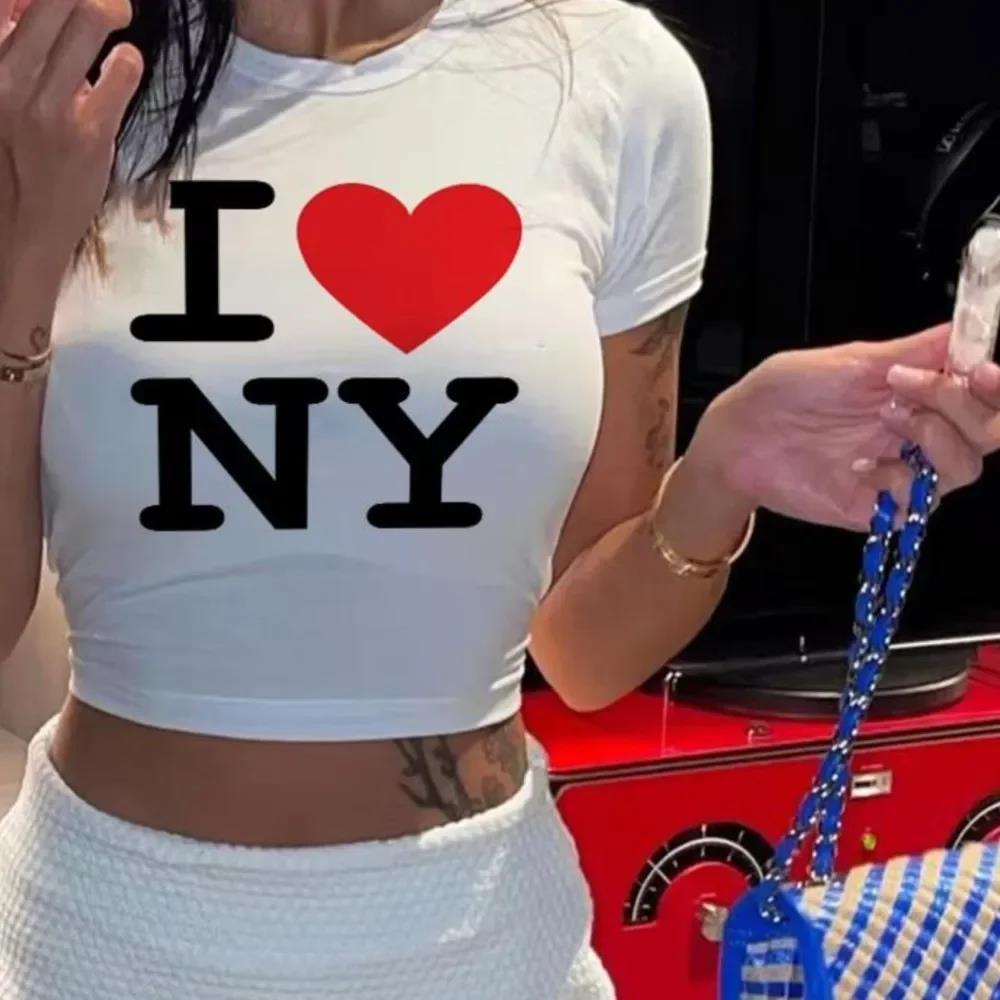 A person wearing a white crop top with the text 'I ❤️ NY' printed on the front.