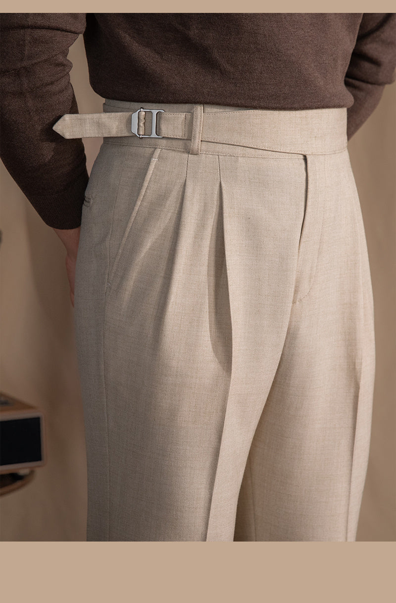 A person standing with hands in pockets, wearing high-waisted trousers in a gray color.