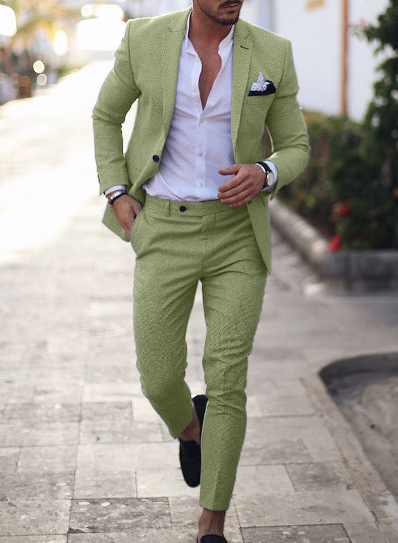 A man wearing a light gray two-piece suit with a white shirt, featuring a tailored fit that enhances body curves.