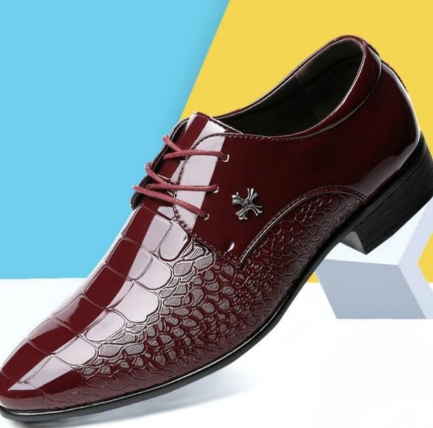 A black pointed toe lace-up shoe with a polished, shiny surface and decorative flower emblem on the vamp.