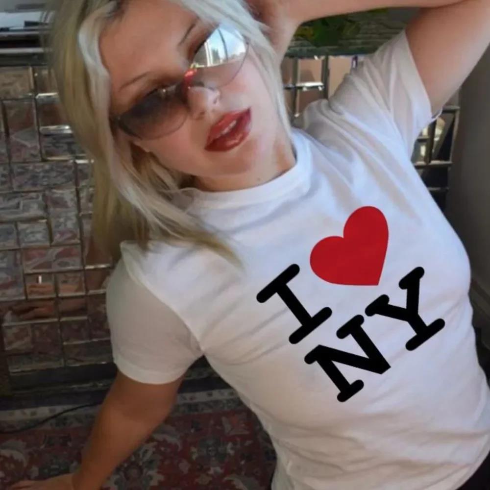 A person wearing a white crop top with the text 'I ❤️ NY' printed on the front.