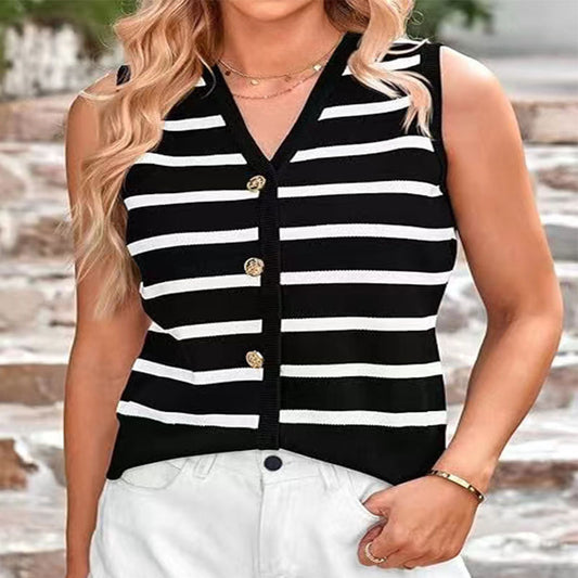 A woman wearing a black and white striped knitted vest with button closures at the front, paired with white shorts.