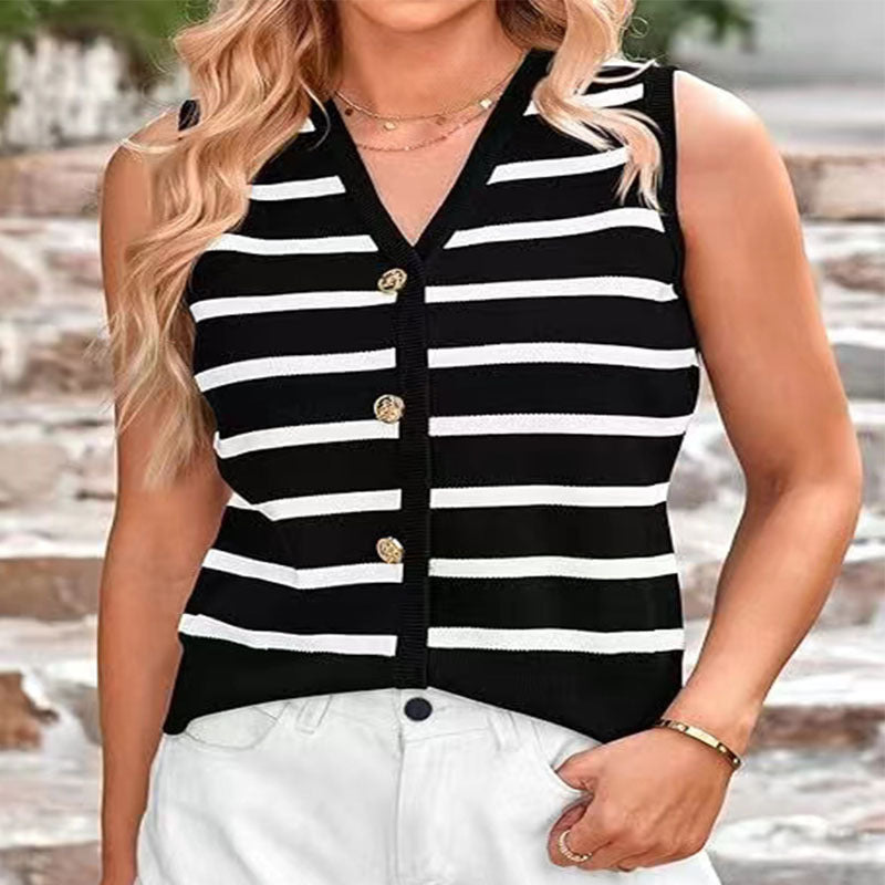 A woman wearing a black and white striped knitted vest with button closures at the front, paired with white shorts.