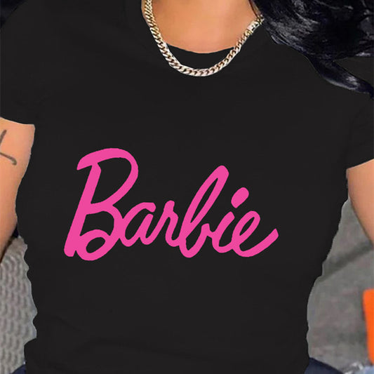 A person wearing a black relaxed fit t-shirt with the pink 'Barbie' text graphic printed on the front.